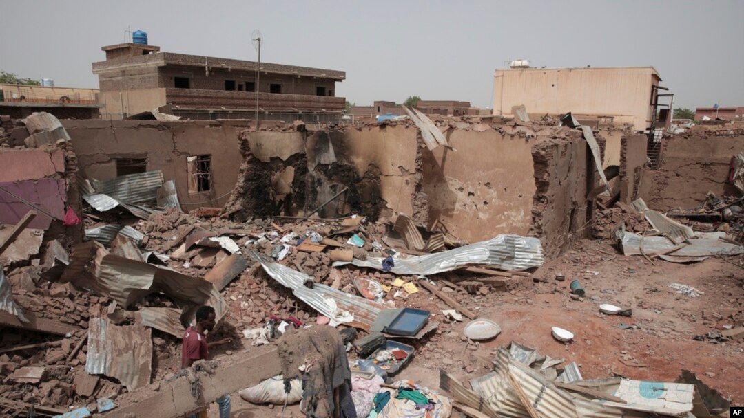 FILE - A man walks by a house hit in fighting in Khartoum, Sudan, an area torn by violence between the military and the notorious paramilitary Rapid Support Forces, April 25, 2023.