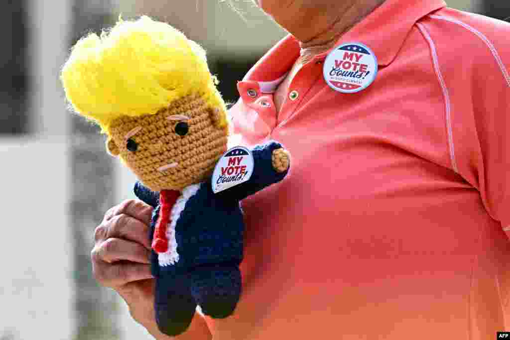 Uyu munyamerikakakazi wo muri reta ya Florida ashigikiye umukandida w'abarepublikane ku mwanya wa prezida, Donald Trump. Afise igikinisho gishushanijeko Trump, n'agapapuro baha kanditseko 'My Voye", ( Uwo natoye).
