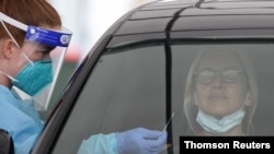 FILE PHOTO: A medical worker swabs a member of the public at a drive-through COVID-19 testing centre in Sydney