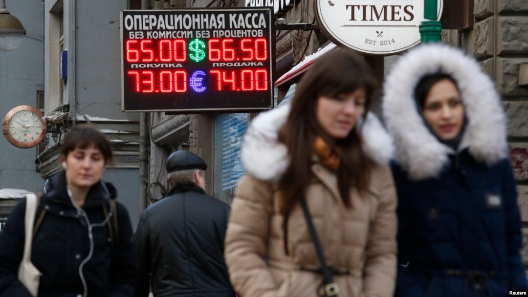 FILE - People walk past a currency exchange rate display in Moscow.