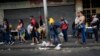 Varias personas hacen fila mientras esperan un transporte público en Caracas, Venezuela, el lunes 27 de febrero de 2023. (Foto AP/Ariana Cubillos)