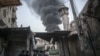 Syrian rebels watch smoke rise as government artillery strike in Jedida district of Aleppo, Syria. November, 2012. (AP)