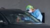 A healthcare worker takes a swab sample from a driver at a drive-through COVID-19 testing site, July 8, 2020, in Miami Gardens, Fla.