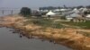 FILE - People are seen by the bank of Benue River in Makurdi, Nigeria.