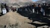 Villagers stand in front of the graves of people killed during an explosion in Sayedabad, Wardak southwest of Kabul, Afghanistan, Jan. 13, 2013. 