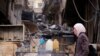 FILE - A woman walks past fuel for sale in Ein Terma, a district of eastern Ghouta, Syria, Feb. 26, 2019. 