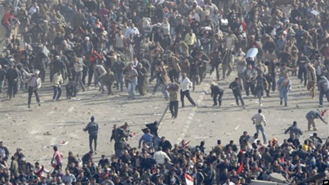 Pro-government demonstrators, below, and anti-government demonstrators, above, clash in Tahrir Square, the center of anti-government demonstrations, in Cairo, Egypt, February 2, 2011