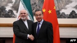 2019年12月31日，中国外长王毅（右）与伊朗外长穆罕默德·贾瓦德·扎里夫（Mohammad Javad Zarif）在北京钓鱼台国宾馆举行的会议上握手。