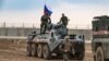 FILE - Russian troops with military vehicles are seen on patrol outside the town of Darbasiyah in Syria's northeastern Hasakeh province, on the border with Turkey, Nov. 1, 2019.