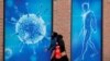 People walk past an illustration of a virus in Oldham, Britain Aug. 3, 2020.