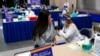 FILE - Tiffany Husak, left, a nursing student at the Community College of Allegheny County, receives her first dose of the Moderna COVID-19 vaccine, during a vaccination clinic in Pittsburgh, Jan. 28, 2021. 