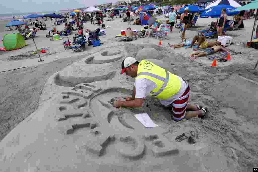 David Burt, with team LS3P and architectural firm out of Charleston, S.C., makes the official eclipse sand castle logo in preparation for the solar eclipse Monday, Aug. 21, 2017, on the beach at Isle of Palms, S.C. The city of Isle of Palms hosted a beach party "Get Eclipsed on IOP". (AP Photo/Mic Smith)
