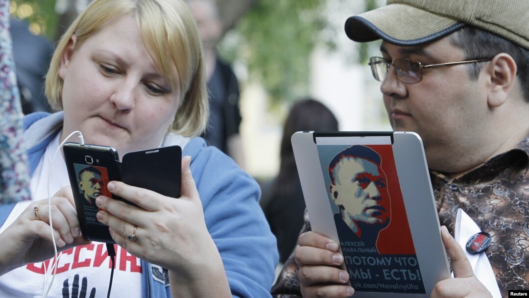 Opposition activists use electronic devices pictured with portraits of prominent anti-corruption blogger Alexei Navalny during a four day-long protest in a boulevard in central Moscow, May 10, 2012.