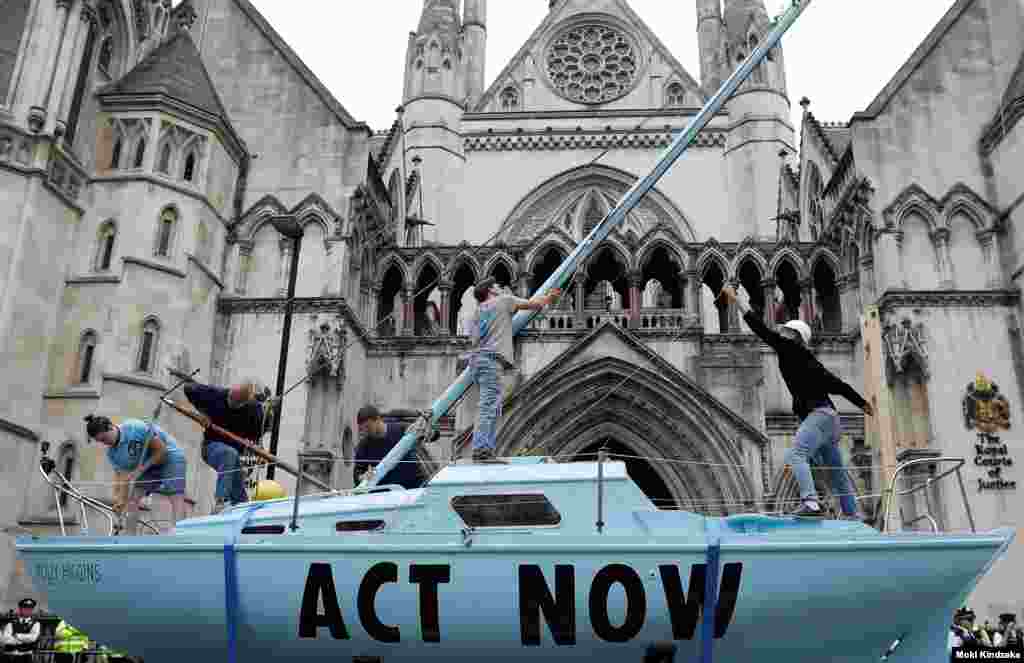 Extinction Rebellion climate activists raise a mast on their boat during a protest outside the Royal Courts of Justice in London.