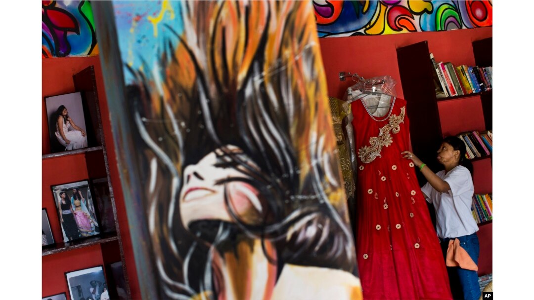 FILE - Acid attack survivor Rupa, 22, arranges some of her creations displayed at "Sheroes Hangout" café, managed by five acid attack survivors in Agra, India, Nov. 25, 2014.