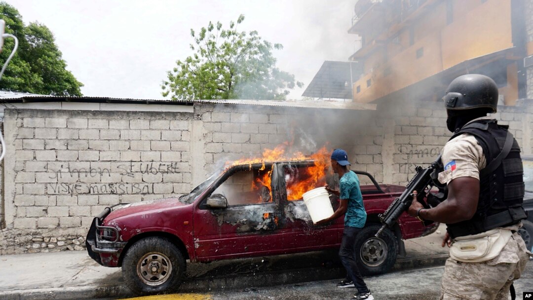 Un trabajador intenta apagar un vehículo en llamas que pertenece a Radio Tele-Ginen durante una protesta que exige la renuncia del presidente Jovenel Moise en Puerto Príncipe, Haití, el lunes 10 de junio de 2019.