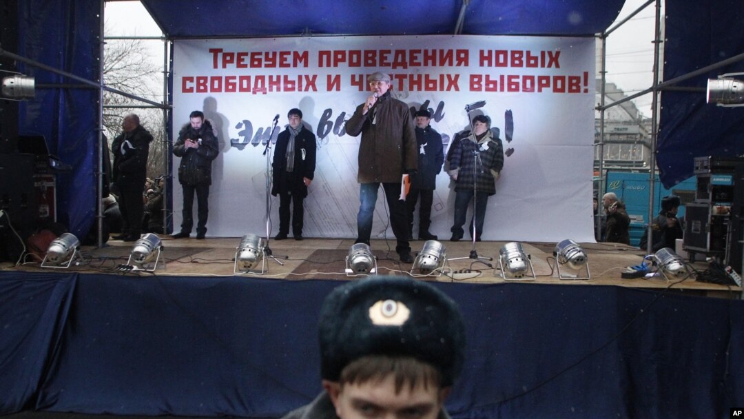 A police officer stands in front of a stage where opposition leader Vladimir Ryzhkov speaks during a mass rally to protest against alleged vote rigging in Russia's parliamentary elections in Moscow, Russia, Saturday, Dec. 10, 2011.
