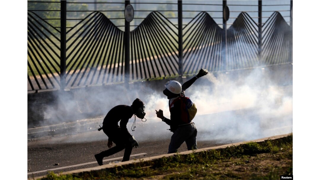 Opposition supporters throw stones into an air base while clashing with riot security forces during a rally against President Nicolas Maduro in Caracas, Venezuela, May 18, 2017.