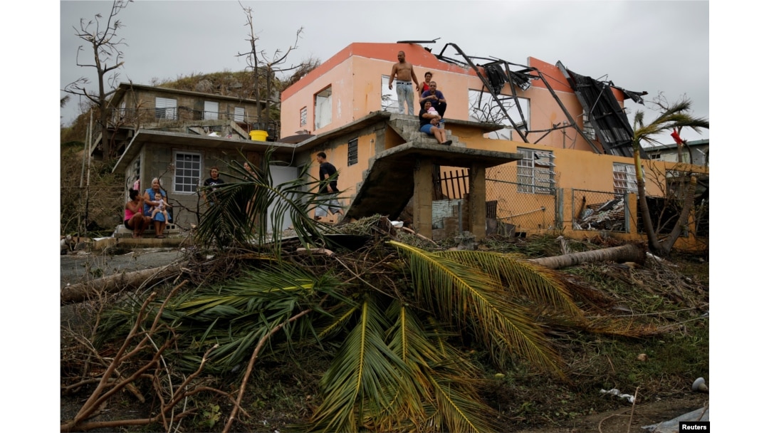 People rest outside a damaged house after the area was hit by Hurricane Maria in Yabucoa, Puerto Rico, Sept. 22, 2017.