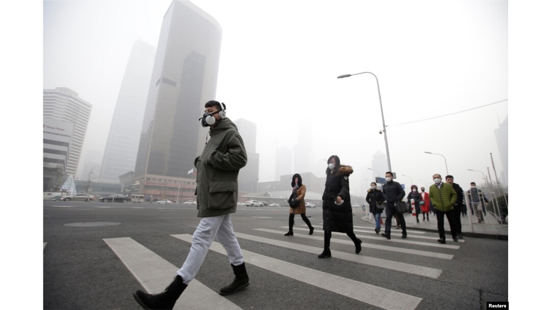 FILE - A man wearing a respiratory protection mask walks toward an office building during the smog after a red alert was issued for heavy air pollution in Beijing's central business district, China, Dec. 21, 2016.