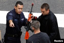 FILE - Police officers pretending to be terrorists receive training weapons during a live counterterrorism demonstration for the 2013 National Homeland Security Conference, in downtown Los Angeles, June 6, 2013.