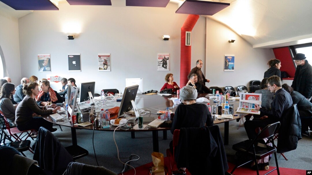FILE - Editorial staff of the French satirical magazine Charlie Hebdo share the offices of the French newspaper Liberation, in Paris, Jan. 9, 2015.
