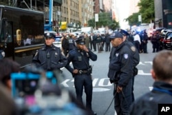 Officers watch over the scene outside the Time Warner Center, Oct. 24, 2018, in New York. Law enforcement officials say a suspicious package that prompted an evacuation of CNN's offices is believed to contain a pipe bomb.