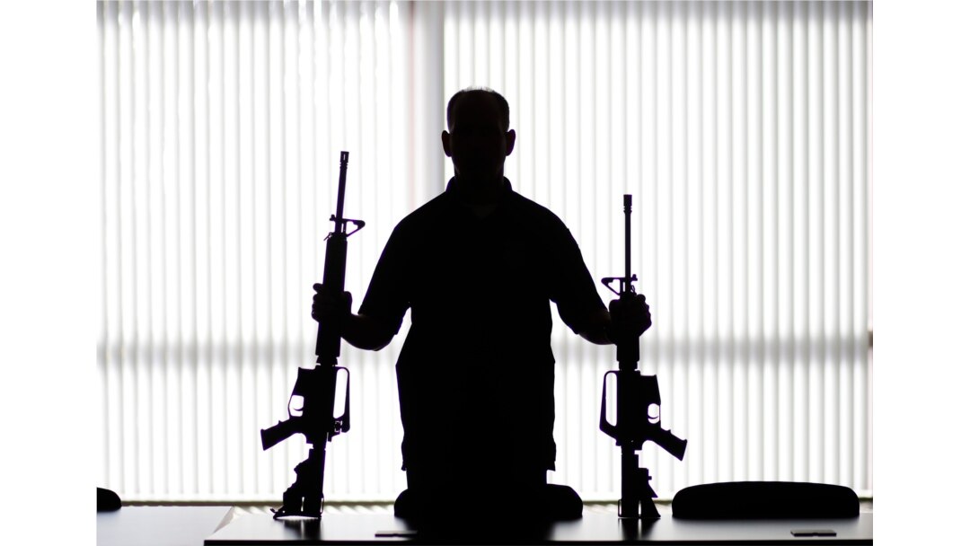 FILE - An agent of the U.S. Bureau of Alcohol, Tobacco, Firearms and Explosives holds guns at an ATF field office in Glendale, Calif., Aug. 29, 2017.