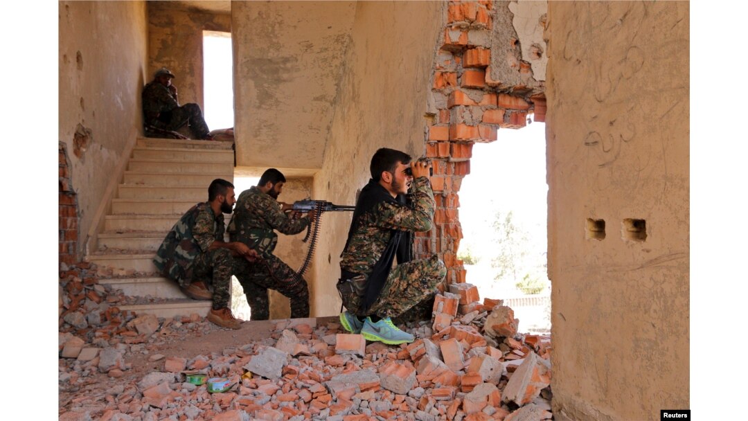 FILE - Kurdish People's Protection Units (YPG) fighters monitor the movements of Islamic State fighters who are stationed nearby, from a damaged building in al-Vilat al-Homor neighborhood in Hasaka city, Syria, July 22, 2015.