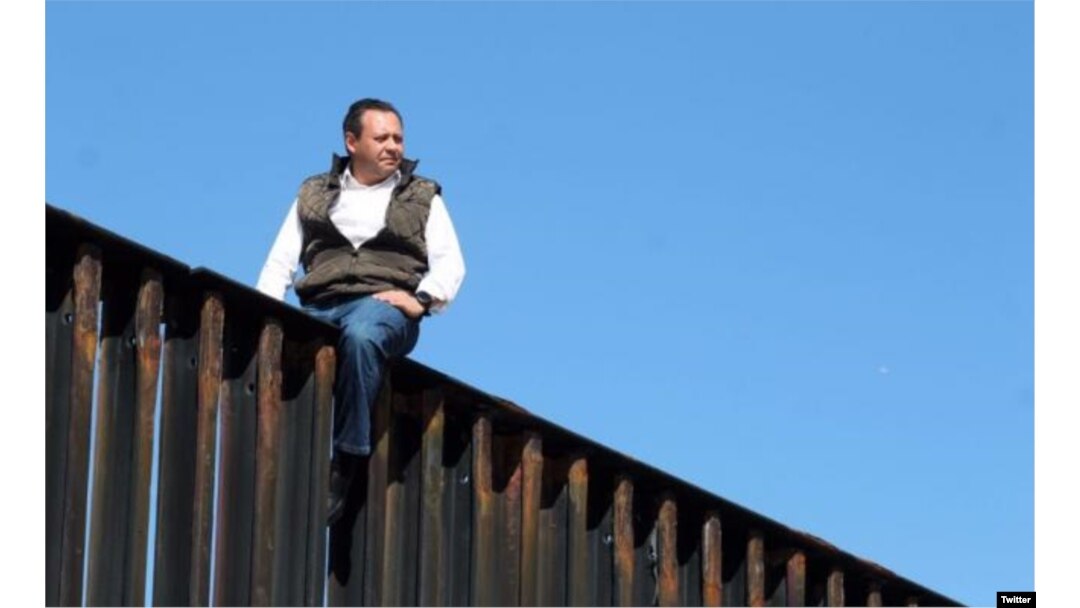 Braulio Guerra, legislador mexicano encima de una valla que divide la frontera entre EE.UU. y México.