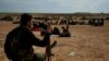 FILE -- A member of U.S.-backed Syrian Democratic Forces (SDF) watches over people who were evacuated out of the last territory held by Islamic State militants, outside Baghouz, Syria, March 5, 2019.