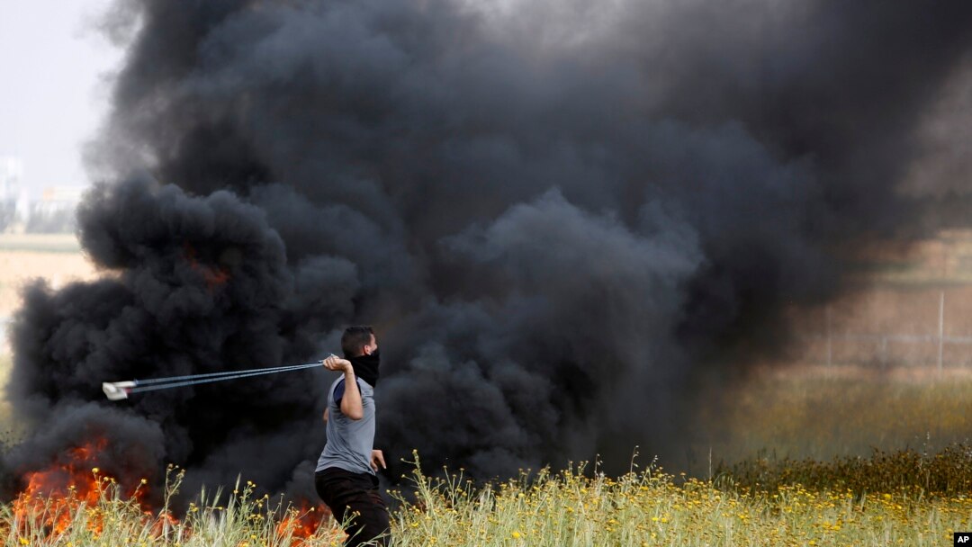 Mpalestina akitupa mawe kuelekea upande wa wanajeshi wa Israeli wakati wa mapambano kati ya waandamanaji wa Palestina na majeshi ya Israeli, huko ukanda wa Gaza Machi 30, 2018