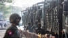 FILE - Soldiers stand next to military vehicles as people gather to protest the military coup in Yangon, Myanmar, on Feb. 15, 2021. Journalists working secretly in Myanmar say they "can be arrested by the military at any time," three years after the coup.