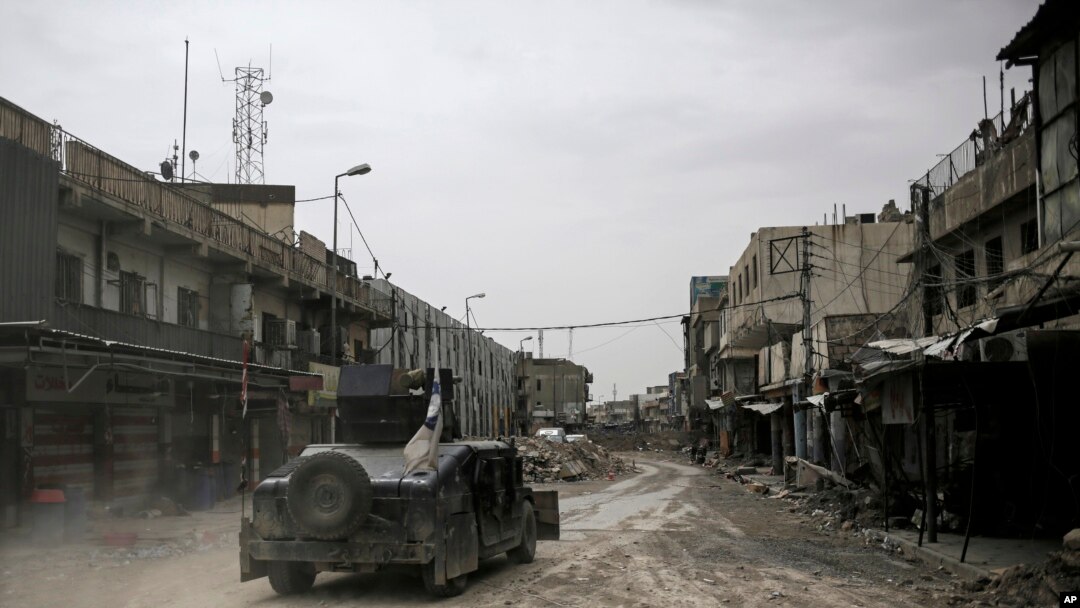 In this Tuesday, May 2, 2017 photo, a humvee of the Iraqi Federal Police drives through an abandoned street in western Mosul, Iraq. 