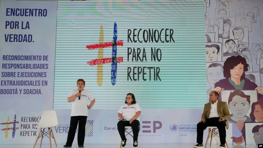 ARCHIVO - Carmenza Gómez (izq), y Gloria Martínez (cent), familiares de asesinados mediante ejecución extrajudicial en 2008, asisten a un evento de reconciliación con el general retirado Paulino Coronado (der), en Soacha, Colombia, el 10 de mayo de 2022.