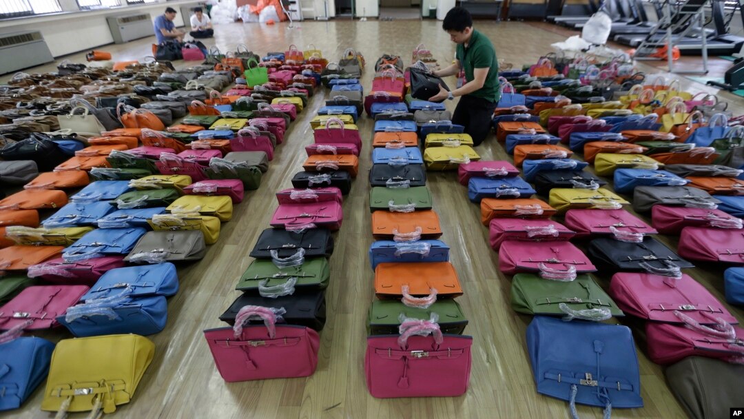 A police official checks some 400 counterfeit bags at the Jungbu police station in Seoul, South Korea, June 1, 2016. 