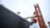 A dock worker wearing a face mask to guard against coronavirus disease (COVID-19) looks at a tanker unloading crude oil at a port in Qingdao, Shandong province, China, March 26, 2020.