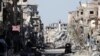 FILE - A fighter of the Syrian Democratic Forces stands amid the ruins of buildings near the Clock Square in Raqqa, Syria, Oct. 18, 2017.