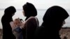 A woman refugee holds her child after arriving with others on a dinghy from Turkey at Lesbos Island, Greece, Sept. 9, 2015. 