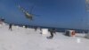 Houthi military helicopter hovers over the Galaxy Leader cargo ship as Houthi fighters walk on the ship's deck in the Red Sea