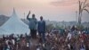 Opposition leader Kizza Besigye, center-left, gestures as he speaks to thousands of his supporters at an election rally at dusk on the outskirts of Kampala, Uganda Sunday, Feb. 14, 2016. 