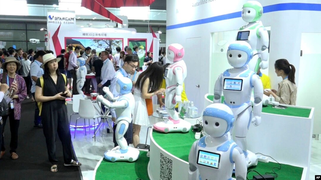 In this image taken from video, visitors look at iPal robots during the Shanghai CES electronic show in Shanghai, China, June 8, 2017. More than 50 companies are showcasing a new generation of robots at this week's Shanghai CES electronics show, most of which serve as companions at home, or butlers in shopping malls. 