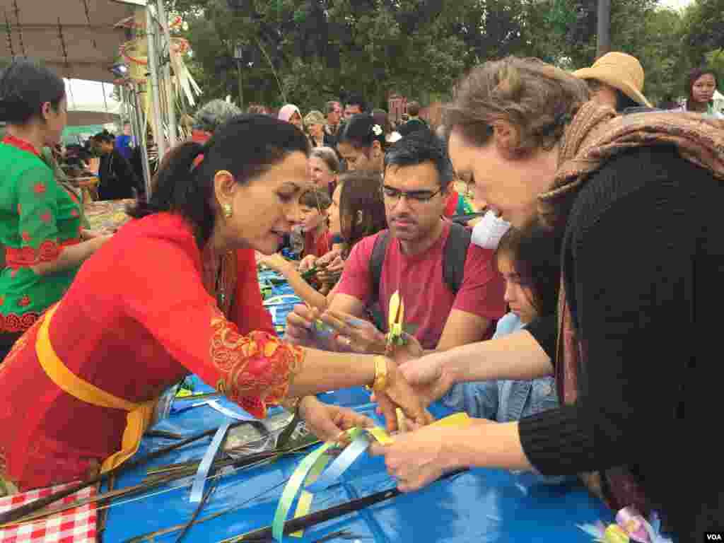 A family learns how to make a janur, a Balinese traditional ornament. (Y. Jung/VOA)