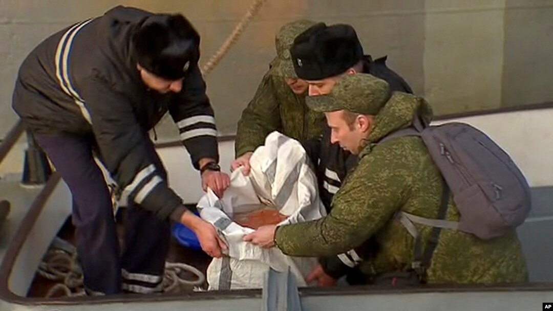 In this Tuesday, Dec. 27, 2016 frame grab made available by Russian Rossiya One TV Channel Emergency Ministry soldiers pack a flight recorder of the crashed plane, on a pier just outside Sochi, Russia.