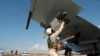 In this photo taken on Oct. 5, 2015, a Russian pilot fixes an air-to-air missile at his Su-30 jet fighter before a take off at Hmeimim airbase in Syria.