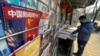 FILE - A newsstand vendor looks through his display near a magazine with a cover depicting U.S. President Joe Biden near U.S. and Chinese flags in Beijing on Jan. 21, 2021.