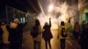 In this photograph taken Jan. 11, 2020, protesters hold flowers as tear gas fired by police rises at a demonstration in front of Amir Kabir University in Tehran, Iran, to remember victims of a Ukrainian airplane shot down by an Iranian missile.