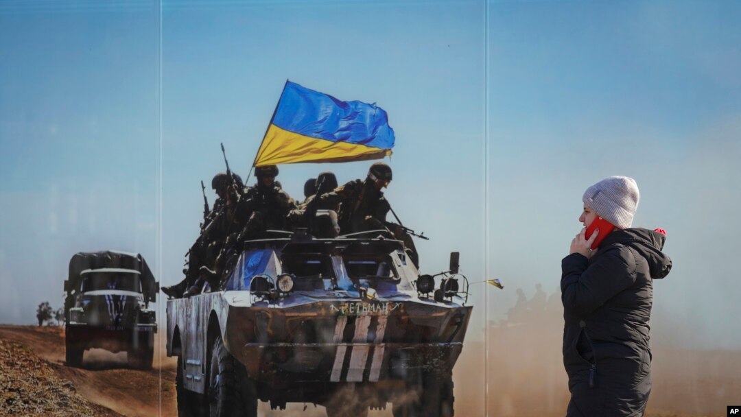 A woman walks by a large print at a photographic memorial for those killed in the confrontation between Ukraine's military and the pro-Russia separatist forces in Sievierodonetsk, Luhansk region, eastern Ukraine, Wednesday, Feb. 23, 2022. (AP Photo/Vadim 
