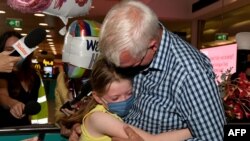 A man hugs his granddaughter Charlotte Roempke upon arriving at Sydney International Airport, Feb. 21, 2022, as Australia reopened its borders for fully vaccinated visa holders, tourists and business travelers. 