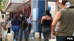Venezolanos hacen fila para llenar de agua sus bidones en Caracas. Foto Carolina Alcalde, VOA.